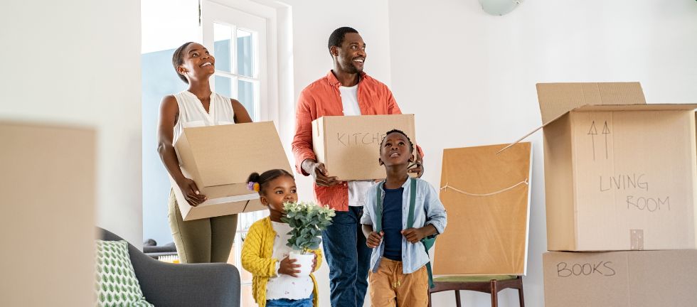 Family carrying moving boxes into their new home