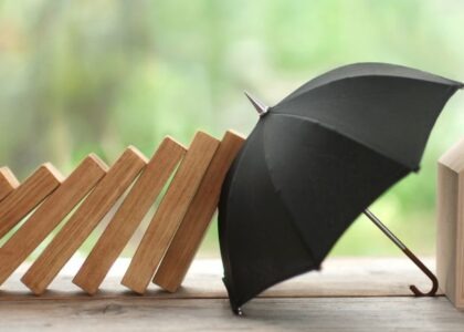 Image illustrating home insurance with an umbrella protecting the house from falling bricks